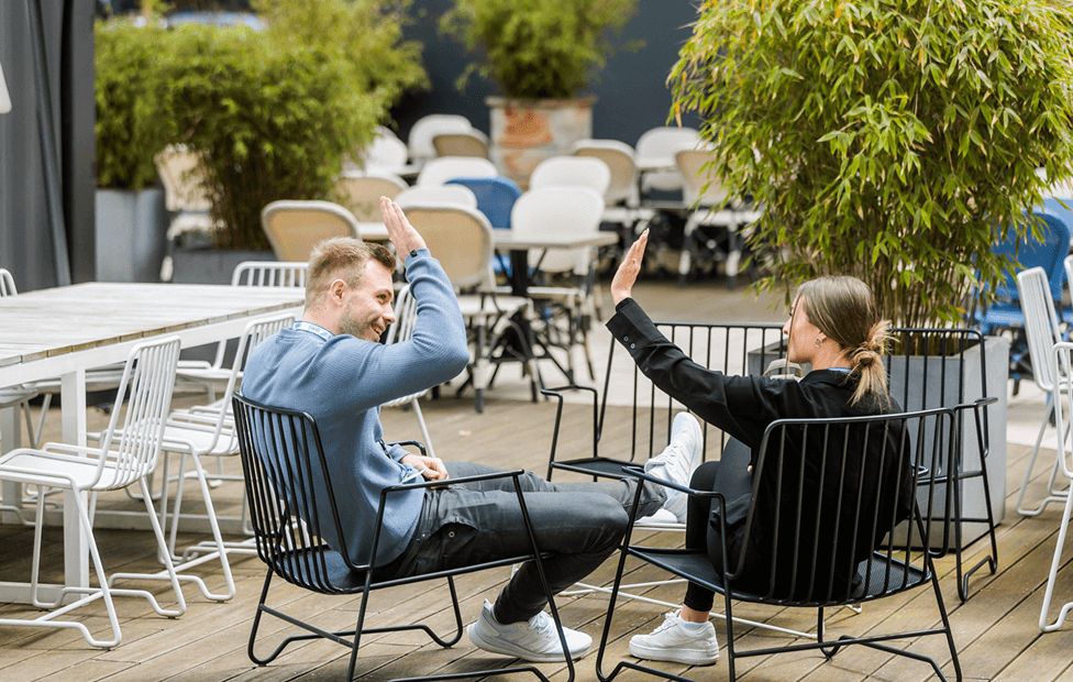 Benjamin Friedrich sitzt neben einer Person und gibt dieser einen High Five